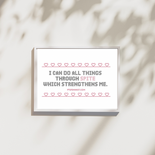 Framed art print of a a quote in cross-stitch black text that reads, “I can do all things through spite which strengthened me.” A cross stitched pink heart border surrounds it.
